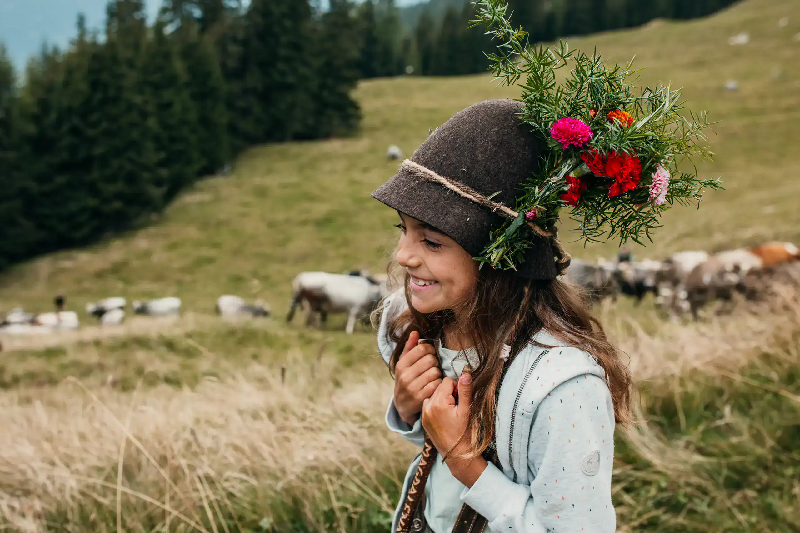 Mädchen mit Blumenkranz auf dem Kopf in ländlicher Landschaft.